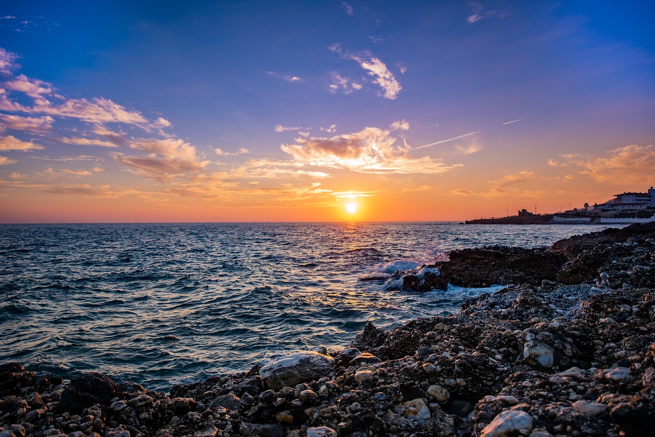Sunset over Playa de la Malagueta with palm trees and gentle waves