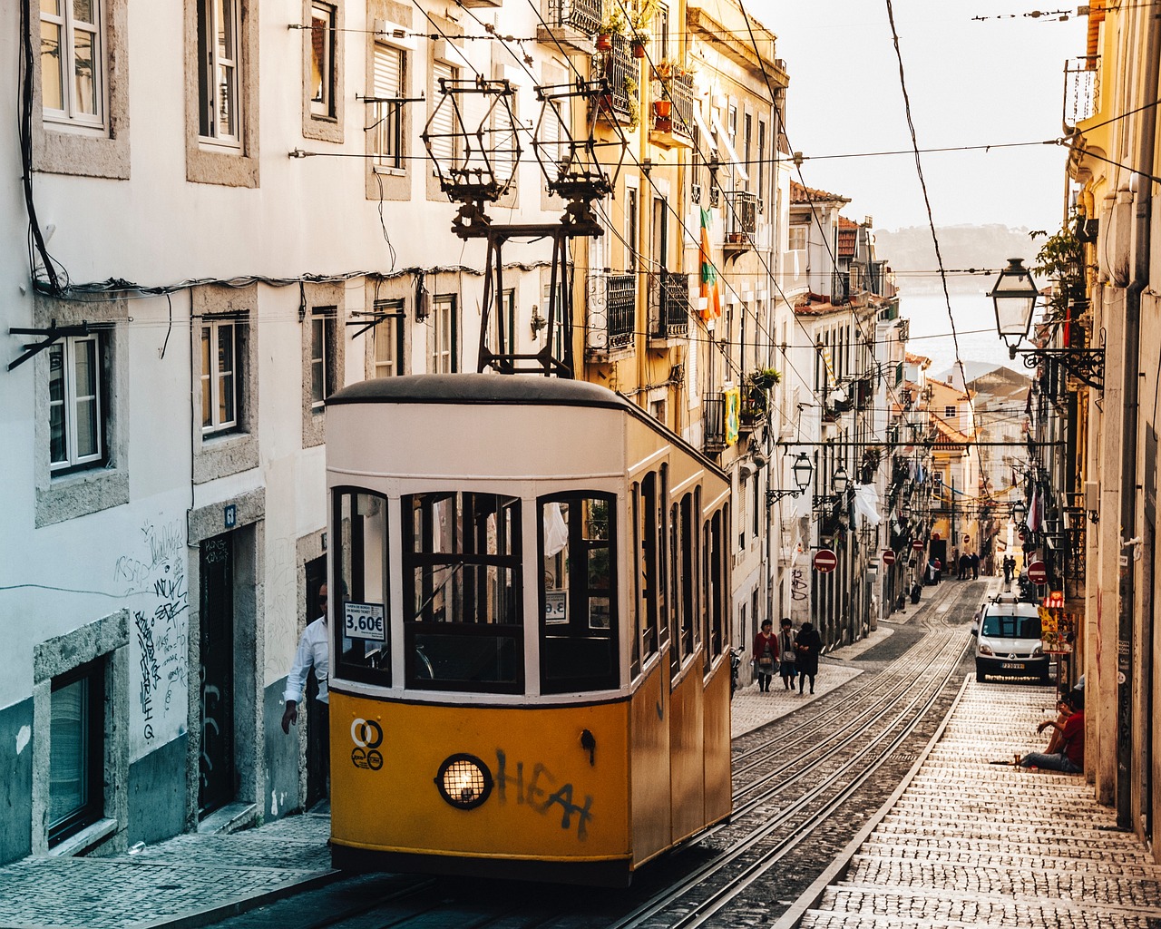 colorful tram passing through historic lisbon neighbourhood with tiled buildings
