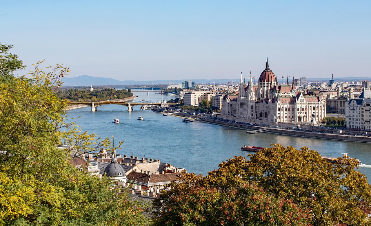 danube river flowing past budapest parliament building at sunset with bridges illuminated